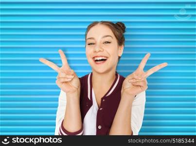 people, gesture and teens concept - happy smiling pretty teenage girl showing peace sign over blue ribbed background. happy smiling teenage girl showing peace sign