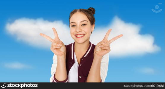 people, gesture and teens concept - happy smiling pretty teenage girl showing peace sign over blue sky and clouds background