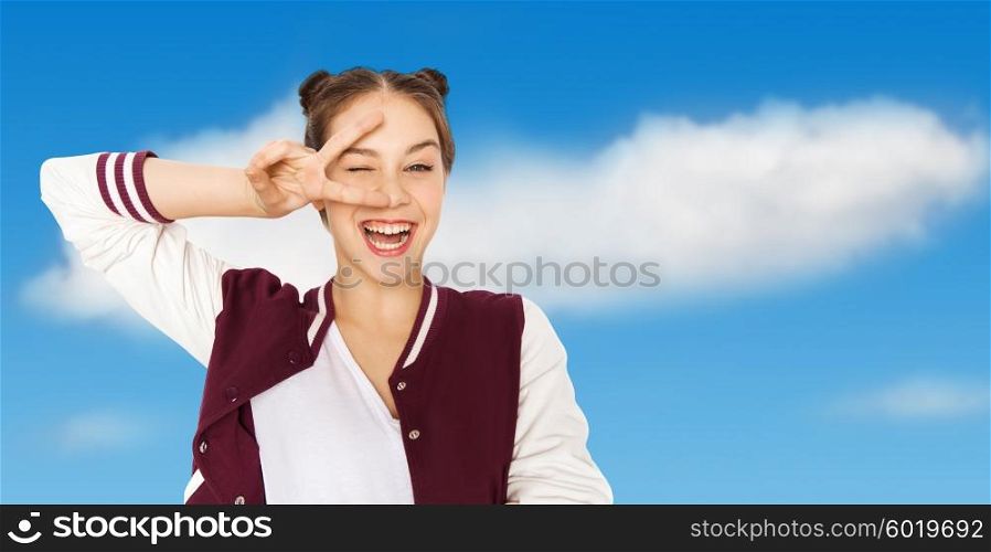 people, gesture and teens concept - happy smiling pretty teenage girl showing peace sign and winking over blue sky and clouds background