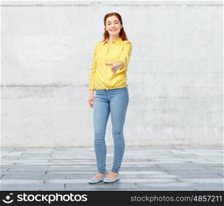 people, gesture, cooperation, partnership and portrait concept - happy young woman giving hand for handshake over stone wall background