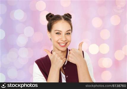 people, gesture, emotions and teens concept - happy smiling pretty teenage girl showing thumbs up over pink holidays lights background