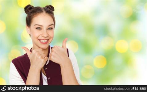 people, gesture, emotions and teens concept - happy smiling pretty teenage girl showing thumbs up over green holidays lights background