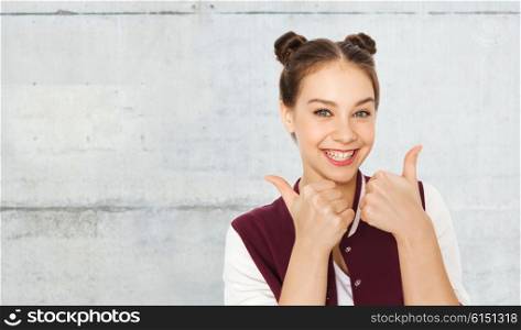 people, gesture, emotions and teens concept - happy smiling pretty teenage girl showing thumbs up over gray concrete wall background showing thumbs up