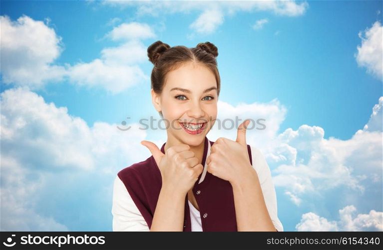 people, gesture, emotions and teens concept - happy smiling pretty teenage girl showing thumbs up over blue sky and clouds background