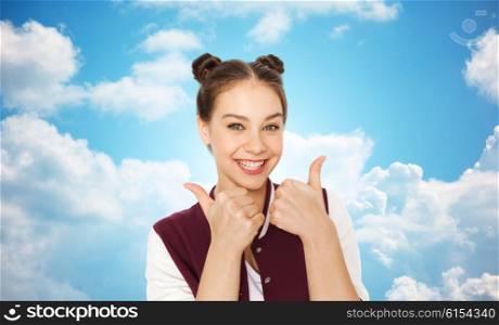 people, gesture, emotions and teens concept - happy smiling pretty teenage girl showing thumbs up over blue sky and clouds background