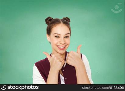 people, gesture, emotions, education and teens concept - happy smiling pretty teenage girl showing thumbs up over green school chalk board background
