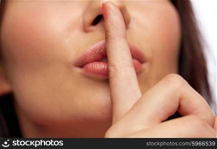 people, gesture, secret and silence concept - close up of woman face holding finger on her lips