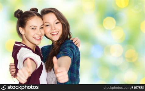 people, gesture, summer, teens and friendship concept - happy smiling pretty teenage girls hugging and showing thumbs up over green holidays lights background