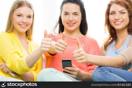 people, gesture, technology and leisure concept - close up of young women or teenage friends with smartphones showing thumbs up at home