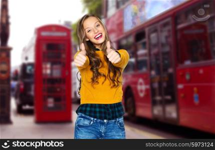 people, gesture, travel, tourism and concept - happy young woman or teen girl in casual clothes showing thumbs up over london city street background