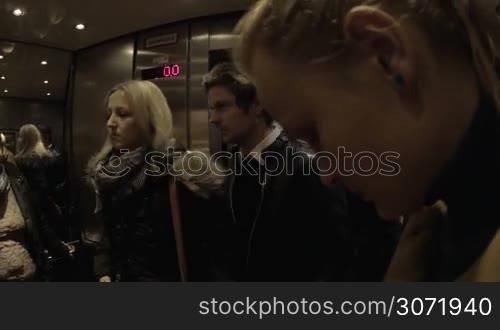 People getting into modern high-speed elevator and standing close to each other