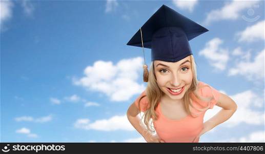 people, graduation and education concept - smiling young student woman in mortarboard over blue sky and clouds background