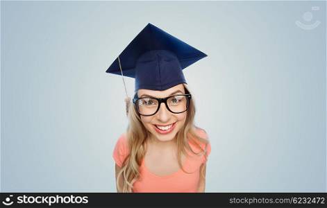 people, graduation and education concept - smiling young student woman in mortarboard and eyeglasses over gray background