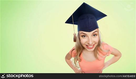 people, graduation and education concept - smiling young student woman in mortarboard over green natural background