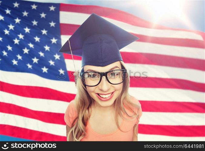 people, graduation and national education concept - smiling young student woman in mortarboard and eyeglasses over american flag background. smiling young student woman in mortarboard