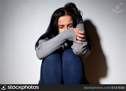 people, grief and domestic violence concept - unhappy woman sitting on floor and crying. unhappy woman crying on floor