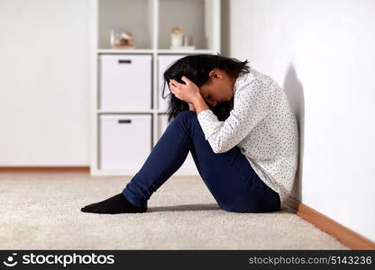 people, grief and domestic violence concept - unhappy woman sitting on floor and crying at home. unhappy woman crying on floor at home