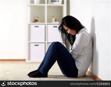 people, grief and domestic violence concept - unhappy woman sitting on floor and crying at home. unhappy woman crying on floor at home
