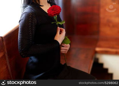 people, grief and mourning concept - close up of woman with red roses sitting on bench at funeral in church. close up of woman with roses at funeral in church