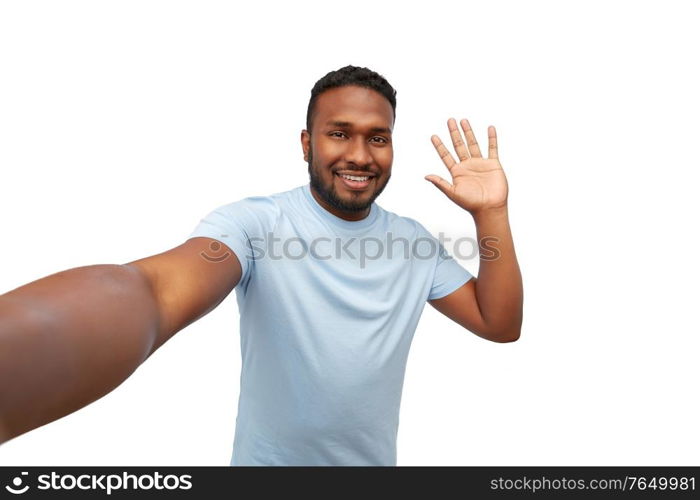 people, grooming and beauty concept - portrait of happy smiling young african american man taking selfie and waving hand over white background. smiling young african american man taking selfie