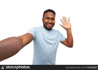 people, grooming and beauty concept - portrait of happy smiling young african american man taking selfie and waving hand over white background. smiling young african american man taking selfie