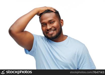 people, grooming and hairstyle concept - portrait of happy smiling young african american man touching his hair over white background. smiling young african american man touching hair