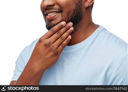 people, grooming and shaving concept - portrait of happy smiling young african american man touching his beard over white background. portrait of smiling young african american man