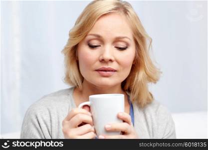 people, guesswork, drinks and leisure concept - woman with cup of tea or coffee at home