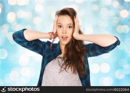 people, hair care, style and teens concept - happy pretty teenage girl holding to head over blue holidays lights background