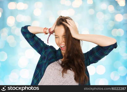 people, hair care, style and teens concept - happy pretty teenage girl holding to head over blue holidays lights background