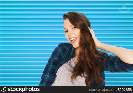 people, hair care, style and teens concept - happy smiling pretty teenage girl touching her head over blue ribbed background. happy smiling pretty teenage girl