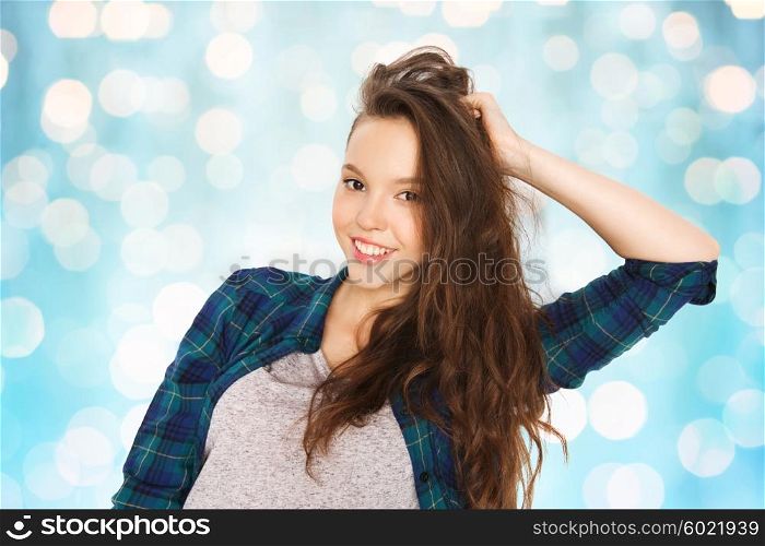 people, hair care, style and teens concept - happy smiling pretty teenage girl touching her head over blue holidays lights background