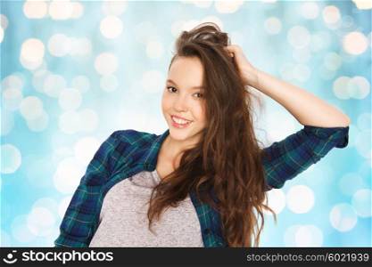 people, hair care, style and teens concept - happy smiling pretty teenage girl touching her head over blue holidays lights background