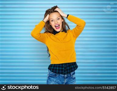 people, hairstyle and fashion concept - happy young woman or teen girl in casual clothes touching hair over blue ribbed wall background. happy young woman or teen girl in casual clothes