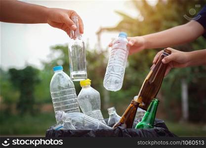 people hand holding garbage bottle plastic and glass putting into recycle bag for cleaning