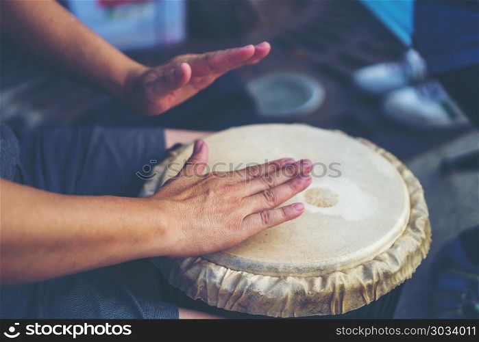 People hands playing music at djembe drums, vintage filter image