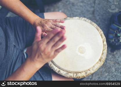 People hands playing music at djembe drums, vintage filter image
