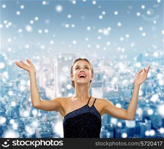 people, happiness, holidays and christmas concept - smiling woman raising hands and looking up over snowy night city background