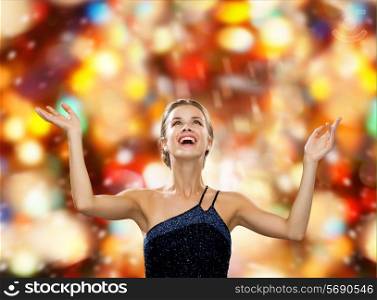 people, happiness, holidays and glamour concept - smiling woman raising hands and looking up over red lights background