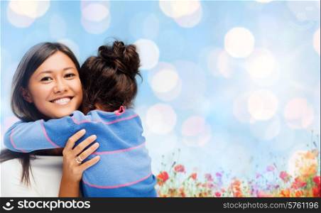 people, happiness, love, family and motherhood concept - happy mother and daughter hugging over blue lights and poppy field background