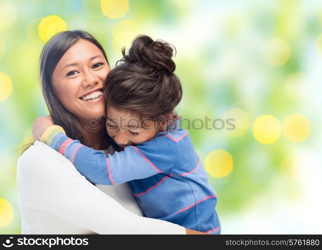 people, happiness, love, family and motherhood concept - happy mother and daughter hugging over green lights background