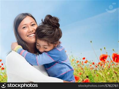 people, happiness, love, family and motherhood concept - happy mother and daughter hugging over blue sky and poppy field background