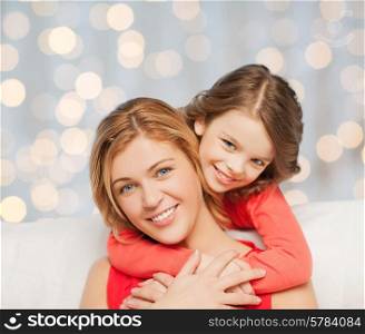 people, happiness, love, family and motherhood concept - happy mother and daughter hugging over holidays lights background