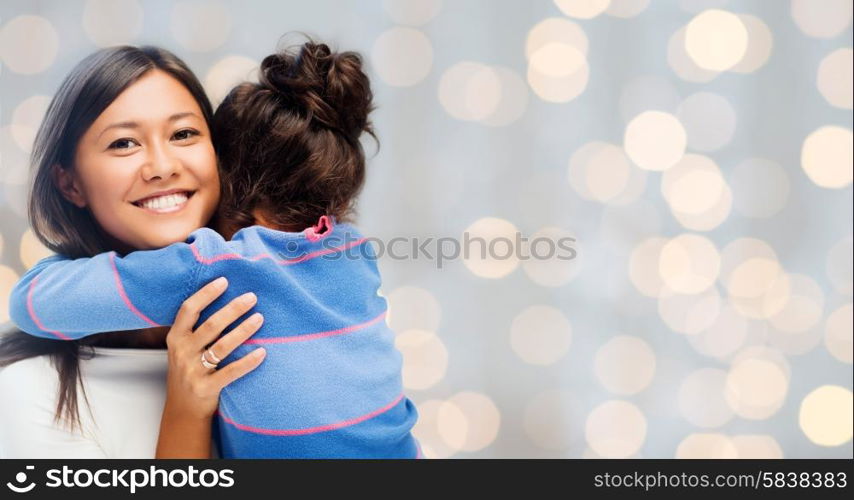 people, happiness, love, family and motherhood concept - happy mother and daughter hugging over holiday lights background