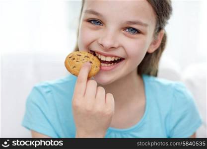 people, happy childhood, food, sweets and bakery concept - smiling little girl eating cookie or biscuit