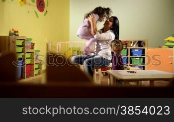 People having fun at school, female educator playing with child in kindergarten