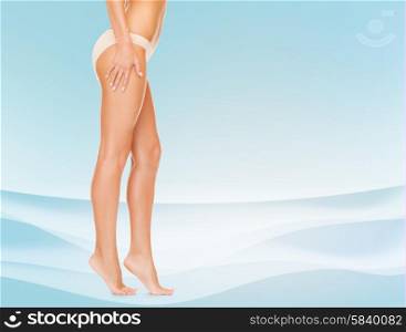 people, health and beauty concept - woman with long legs in cotton panties touching her hips and walking tiptoes over blue background