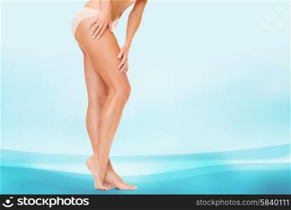 people, health and beauty concept - woman with long legs in cotton panties touching her hips over blue background