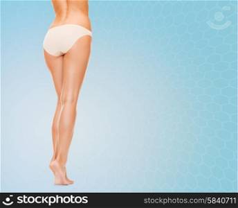 people, health and beauty concept - woman with long legs in cotton panties from back over blue background