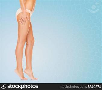 people, health and beauty concept - woman with long legs in cotton panties walking tiptoe over blue background